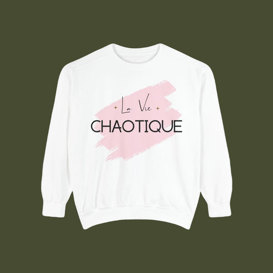 A white crewneck sweatshirt featuring a pink brushstroke graphic on the chest with the text 'La Vie CHAOTIQUE' in black and pink, displayed against a solid white background.