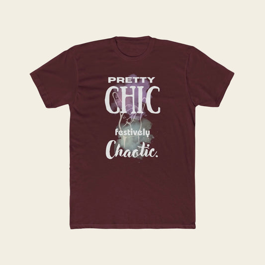 A maroon short-sleeve crewneck t-shirt with a graphic print on the front that reads 'PRETTY CHIC festively Chaotic.' in white and light purple text over a faint festive illustration, displayed on a solid white background.