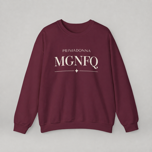 A maroon crewneck sweatshirt featuring cream-colored “PRIMADONNA MGNFQ” text on the chest, accented with a decorative line and small diamond detail, against a neutral gray background.