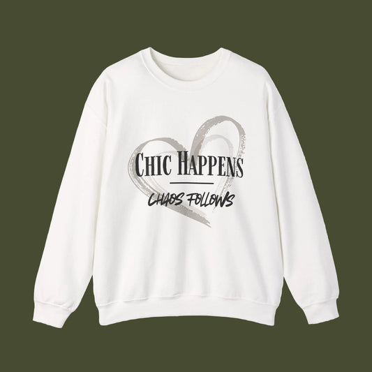 An off-white crewneck sweatshirt featuring a graphic print on the front with a gray brushstroke heart and the text 'CHIC HAPPENS CHAOS FOLLOWS' in black and gray.