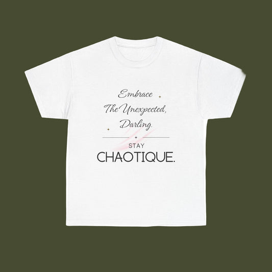 A white short-sleeve crewneck t-shirt with a typographic graphic on the front. The design features the phrase 'Embrace The Unexpected, Darling' in a cursive font, a thin horizontal line, the word 'STAY' in a block font, and 'CHAOTIQUE.