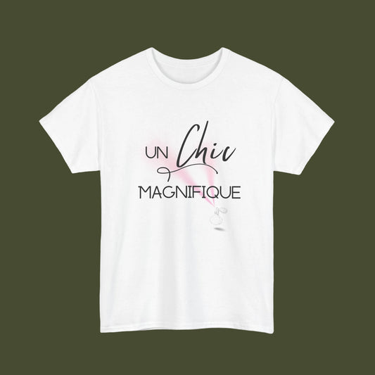 A white short-sleeve crewneck t-shirt featuring a French graphic print that reads 'UN Chic MAGNIFIQUE' in black script and block lettering, accented with a soft pink watercolor splash and a small white feather illustration.