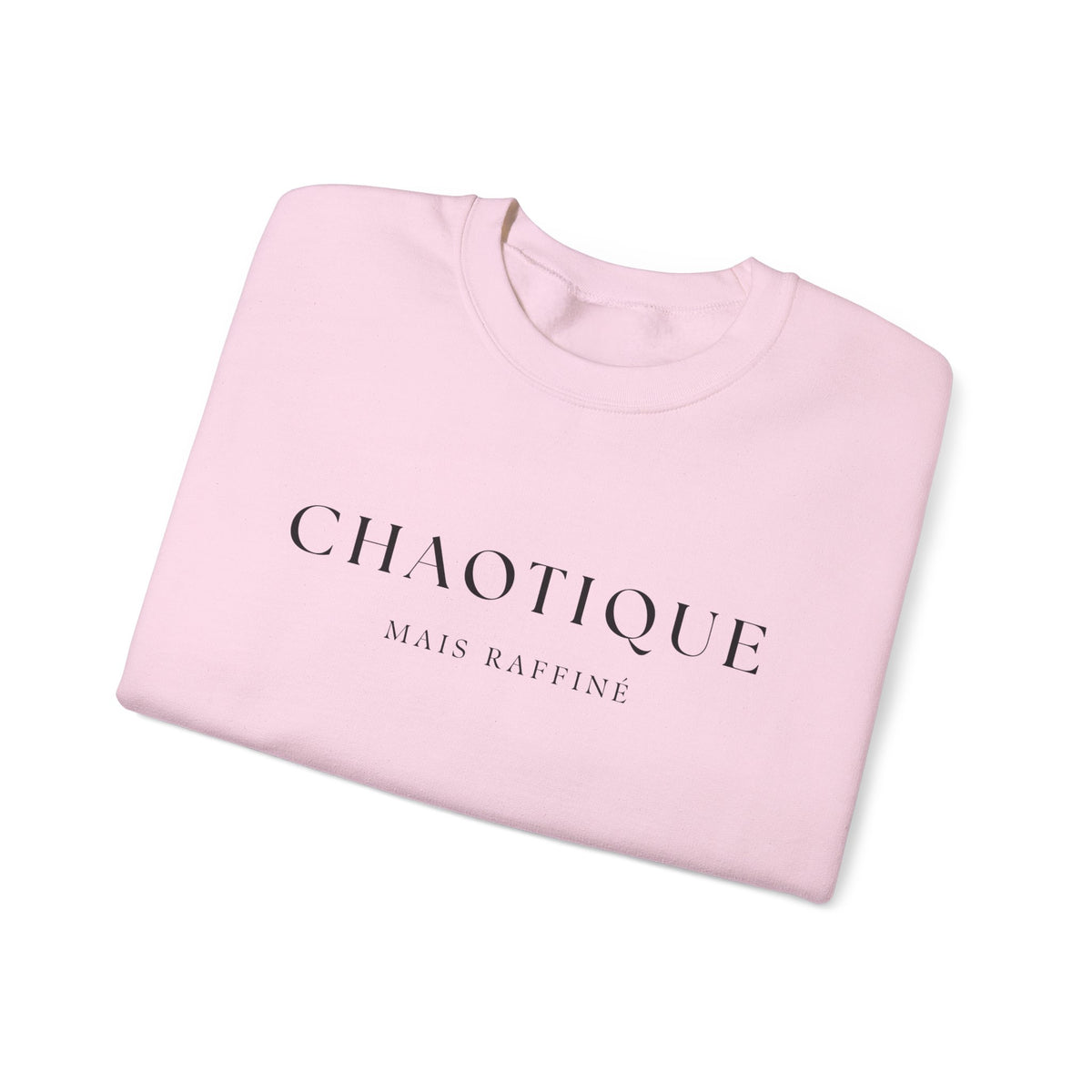 Folded pink sweatshirt with 'Chaotique Mais Raffine' text on a white background