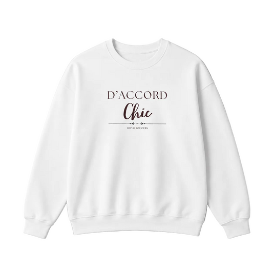 White D’Accord Chic crewneck sweatshirt with dark brown chest typography, displayed flat against a neutral grey studio background.