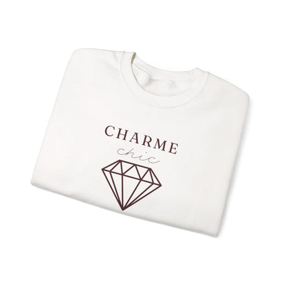 A folded white crewneck sweatshirt featuring a burgundy graphic print that reads 'CHARME chic' above a diamond outline, set against a plain white background.