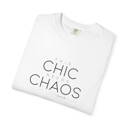 A folded white crewneck t-shirt with the text 'THIS CHIC NEEDS CHAOS' printed in black on the front, displayed on a clean white background.