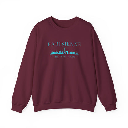 A maroon crewneck sweatshirt with a bright turquoise “PARISIENNE” graphic, Paris skyline design, and “CHIC À MA FAÇON” text on the chest, displayed against a clean white background.