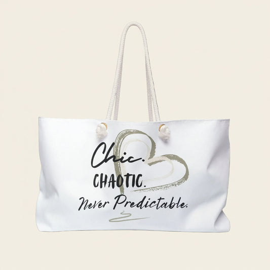 A white tote bag with cream rope handles, featuring a graphic print of a heart and the text 'Chic. CHAOTIC. Never predictable'