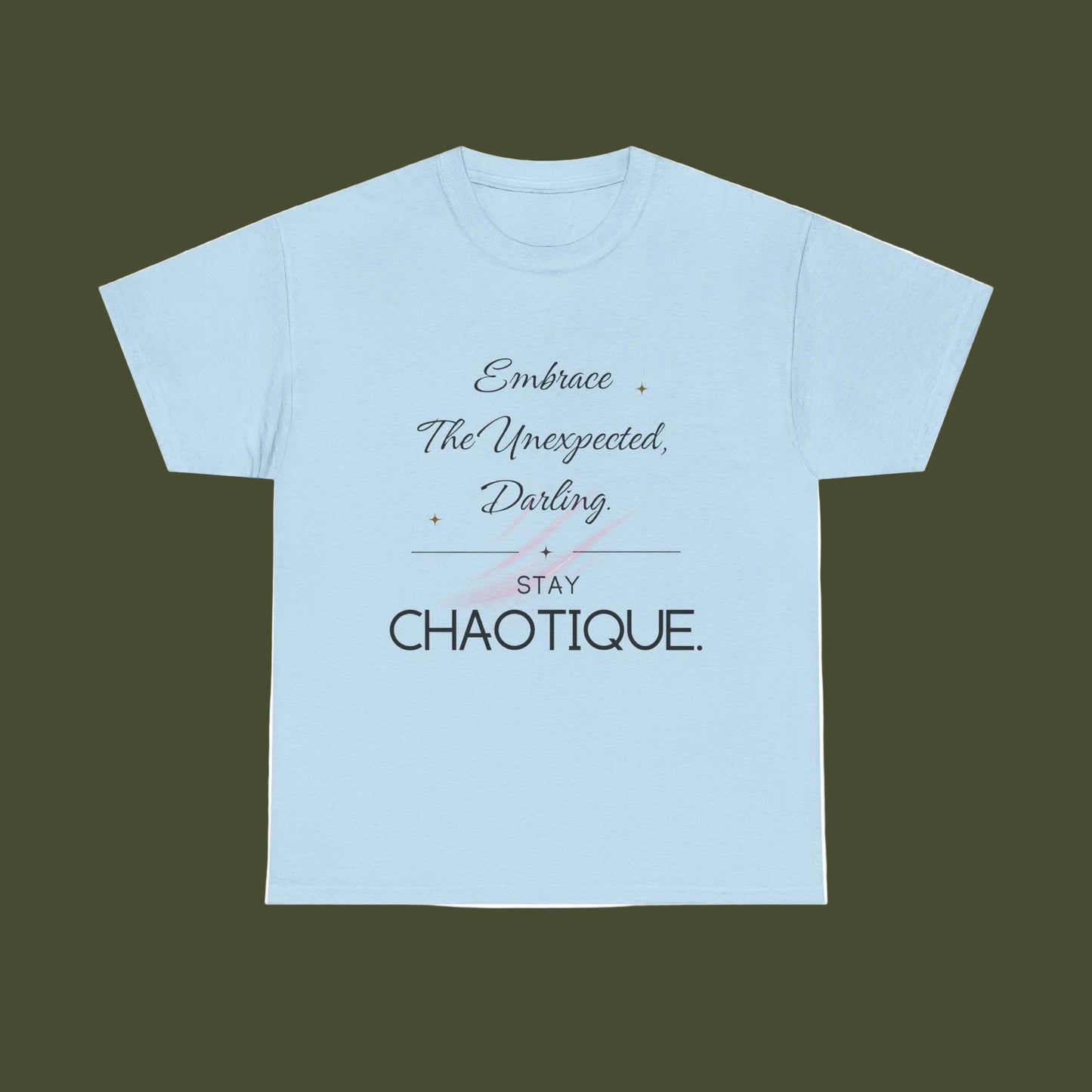 A light blue short-sleeve crewneck t-shirt with a graphic text print on the front reading 'Embrace The Unexpected, Darling STAY CHAOTIQUE.' in black and gray lettering with a small pink bow illustration, displayed on a solid white background.