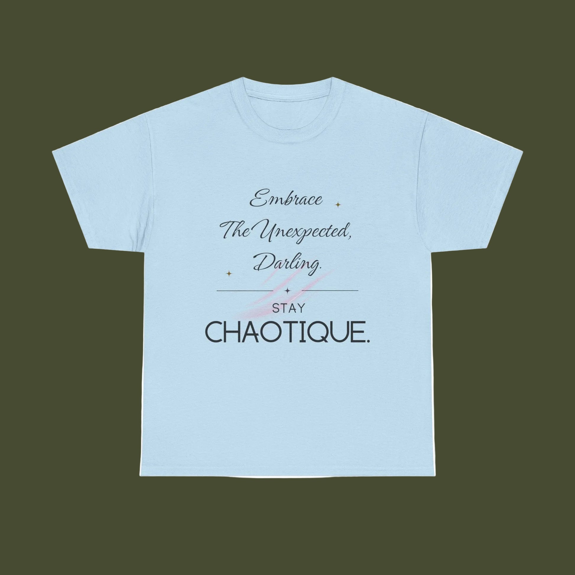 A light blue short-sleeve crewneck t-shirt with a graphic text print on the front reading 'Embrace The Unexpected, Darling STAY CHAOTIQUE.' in black and gray lettering with a small pink bow illustration, displayed on a solid white background.