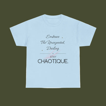 A light blue short-sleeve crewneck t-shirt with a graphic text print on the front reading 'Embrace The Unexpected, Darling STAY CHAOTIQUE.' in black and gray lettering with a small pink bow illustration, displayed on a solid white background.