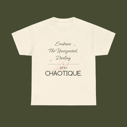 An off-white short-sleeve t-shirt with a printed graphic on the front. The graphic features the text 'Embrace The Unexpected, Darling' in a cursive font, a thin horizontal line, 'STAY' in a block font, and 'CHAOTIQUE.