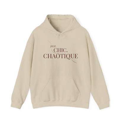 A beige Jolie Chic Chaotique Hoodie featuring an elegant “JOLIE. CHIC. CHAOTIQUE” typography graphic on the front, displayed against a clean white background.