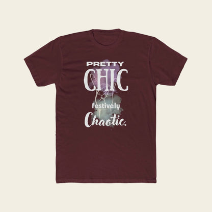 A maroon short-sleeve crewneck t-shirt with a graphic print on the front that reads 'PRETTY CHIC festively Chaotic.' in white and light purple text over a faint festive illustration, displayed on a solid white background.