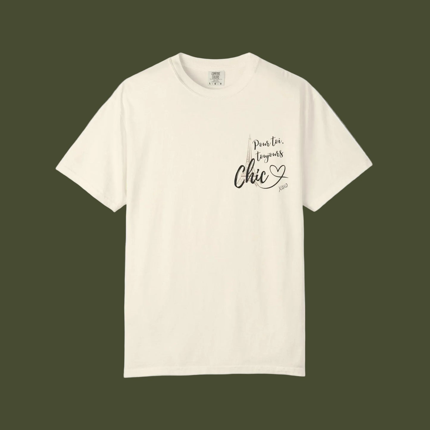 An off-white short-sleeve crewneck t-shirt with a black graphic print on the left chest reading 'Pour toi toujours CHIC. Lugnas Chic 2023' with a small heart and feather detail, displayed on a clean white background.
