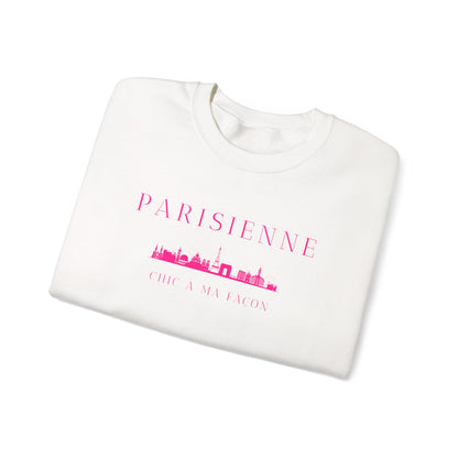 A folded o crewneck sweatshirt with a bright pink “PARISIENNE” graphic, Paris skyline design, and “CHIC À MA FAÇON” text on the chest, displayed against a clean white background.fwhite