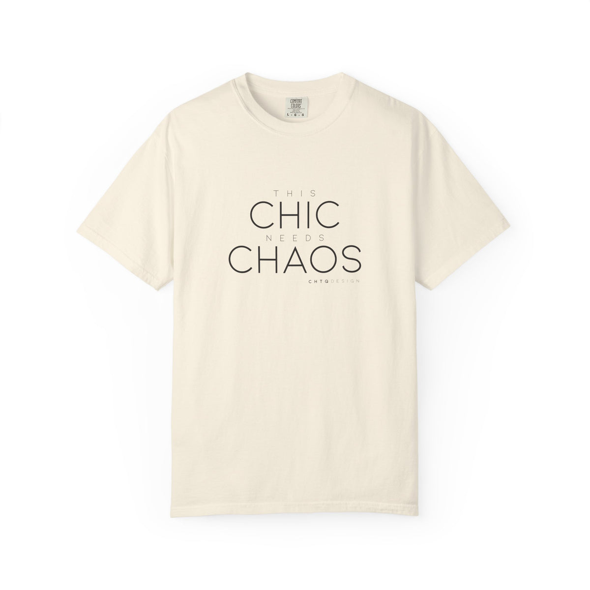 An light beige crewneck t-shirt with the text 'THIS CHIC NEEDS CHAOS' printed in black on the front, displayed on a clean white background.