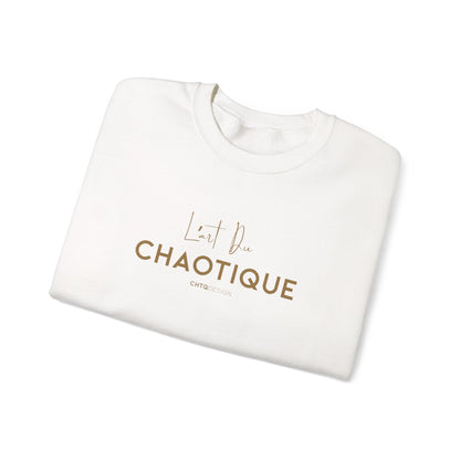 A folded white crewneck sweatshirt with 'L'art Du CHAOTIQUE' printed in brown across the chest, displayed on a clean white background.