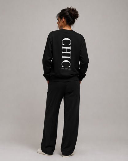 A model shown from the back wearing a black sweatshirt and matching sweatpants set. The sweatshirt features a large vertical white 'CHIC' logo on the back with smaller text underneath.