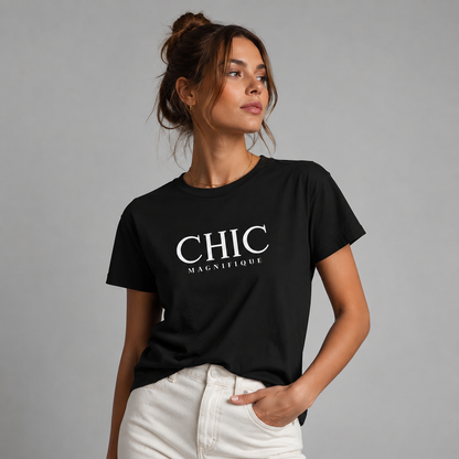 Woman wearing a black CHIC MAGNIFIQUE graphic T-shirt with white French-inspired typography, paired with off-white trousers in a neutral gray studio setting.
