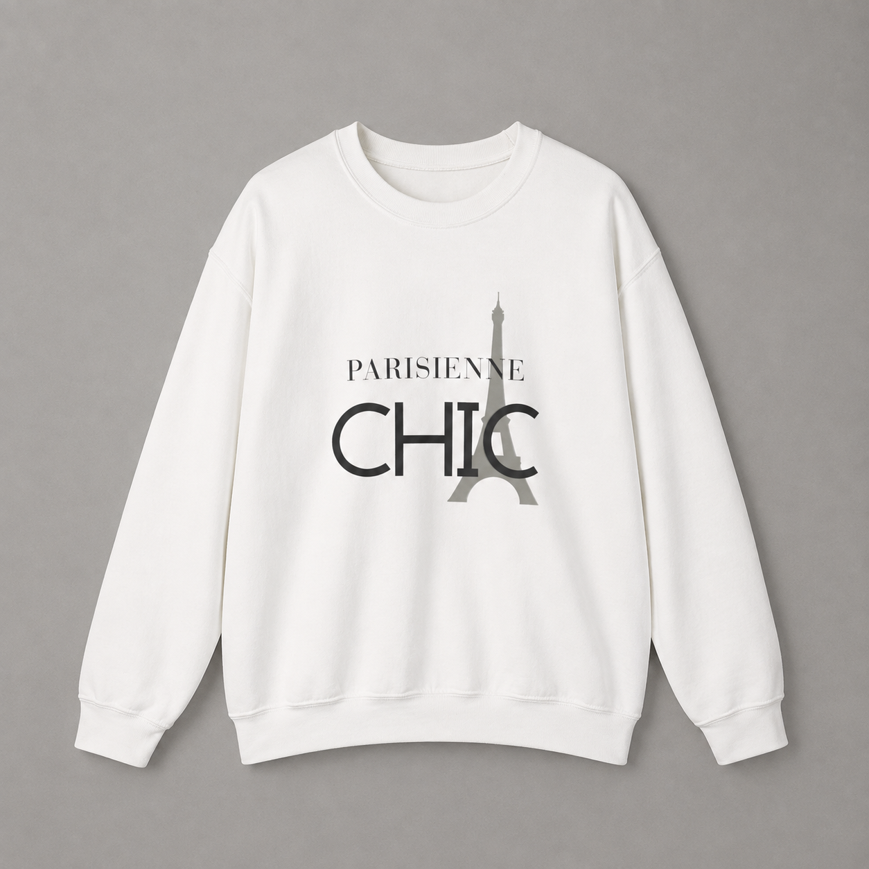 White crewneck sweatshirt featuring a black “PARISIENNE CHIC” graphic with a stylized Eiffel Tower, displayed against a neutral gray studio background.
