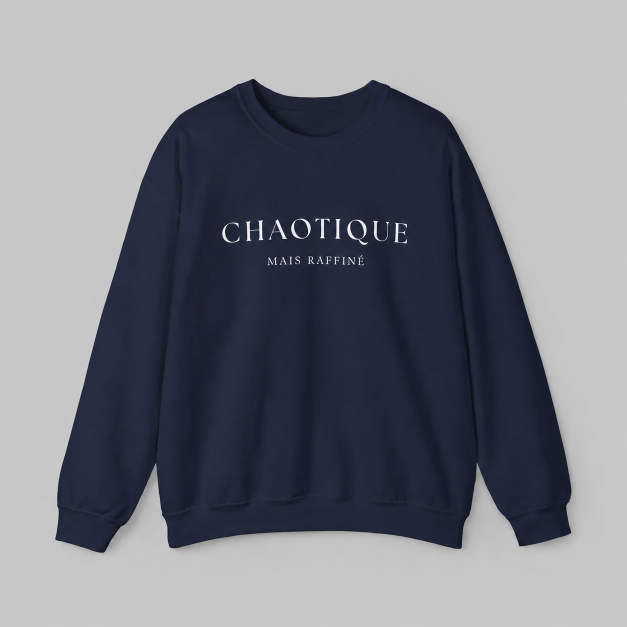 Navy blue sweatshirt on a white background featuring a “Chaotique Mais Raffiné” graphic text print.