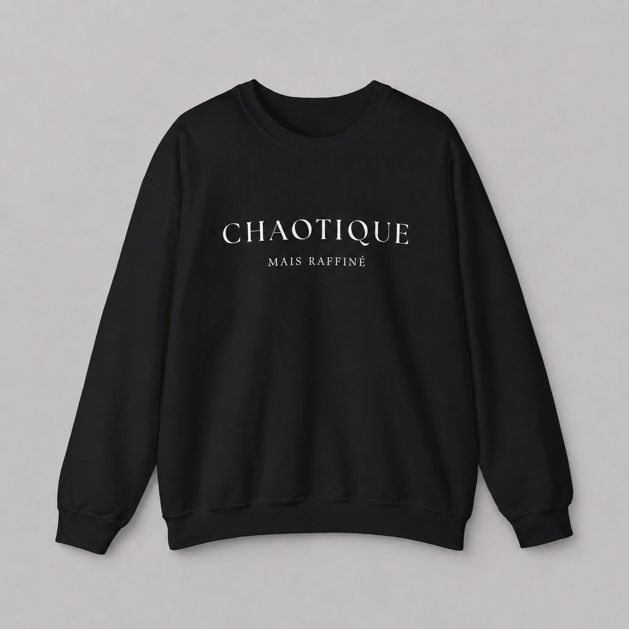 Black sweatshirt on a white background featuring a “Chaotique Mais Raffiné” graphic text print.
