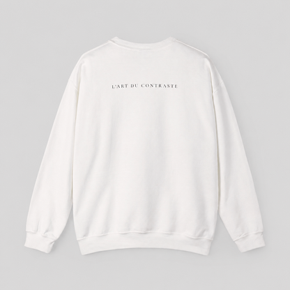 A white long-sleeve crewneck sweatshirt shown from the back, featuring the black printed text 'L'ART DU CONTRASTE' centered across the upper back, set against a solid light gray background.