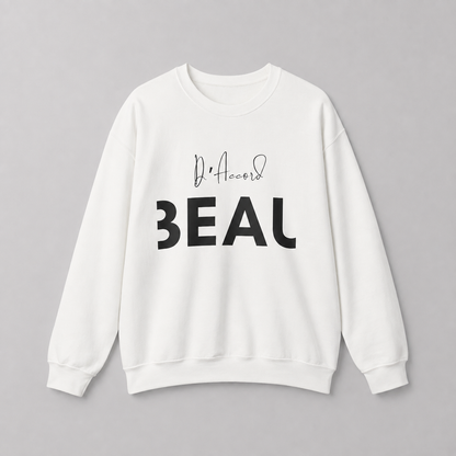 A white crewneck sweatshirt featuring a black “D’accord” script graphic above bold “BEAU” lettering across the chest, displayed against a neutral light gray background.