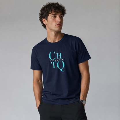 A man wearing a navy blue crewneck T-shirt featuring a light blue “CHTQ” graphic with “ELEGANZA” lettering on the chest, paired with black trousers and photographed against a light gray studio background.