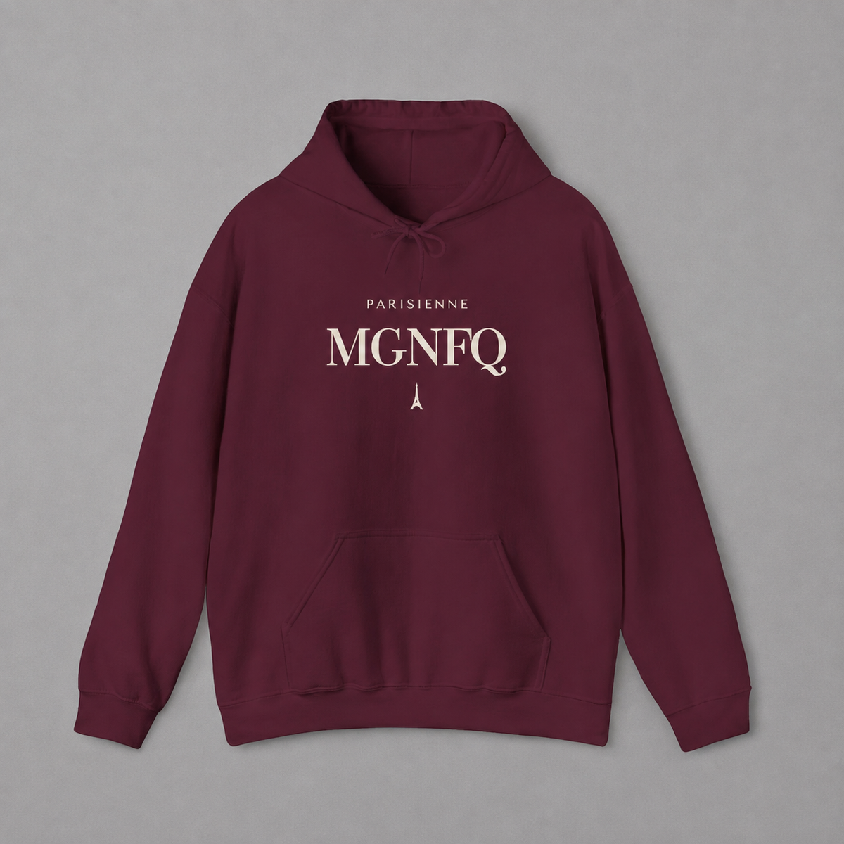 Maroon PARISIENNE MGNFQ graphic hoodie featuring cream typography and a small Eiffel Tower detail, shown against a light gray studio background.
