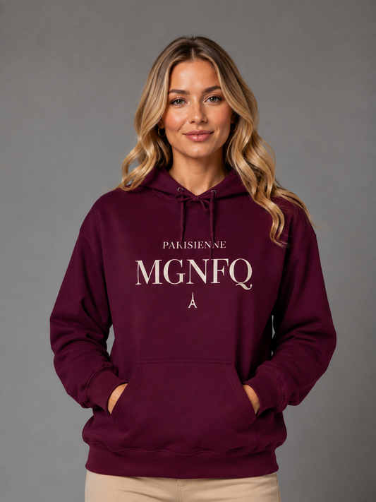 A woman wearing a burgundy PARISIENNE MGNFQ graphic hoodie with cream typography, posing against a neutral gray studio background.