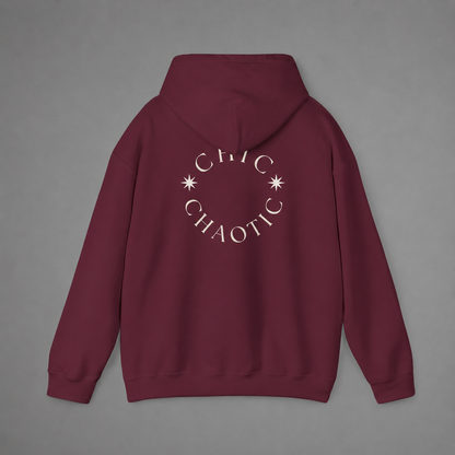 Maroon pullover hoodie shown from the back, featuring a dark burgundy circular CHIC CHAOTIC graphic with subtle star accents against a neutral gray studio background.