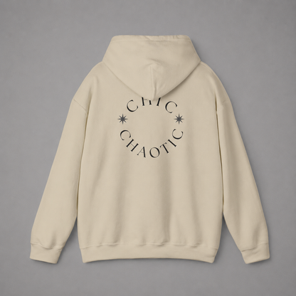 Beige pullover hoodie shown from the back, featuring a dark burgundy circular CHIC CHAOTIC graphic with subtle star accents against a neutral gray studio background.