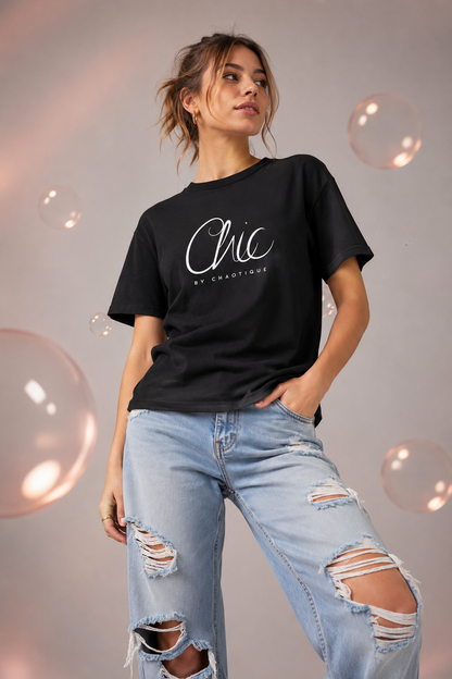 Woman wearing a black Chic by Chaotique graphic T-shirt with light blue ripped jeans in a modern studio setting.
