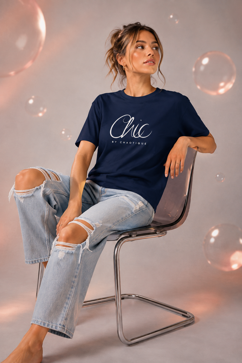 Woman wearing a navy blue Chic by Chaotique graphic T-shirt with light blue ripped jeans in a modern studio setting.