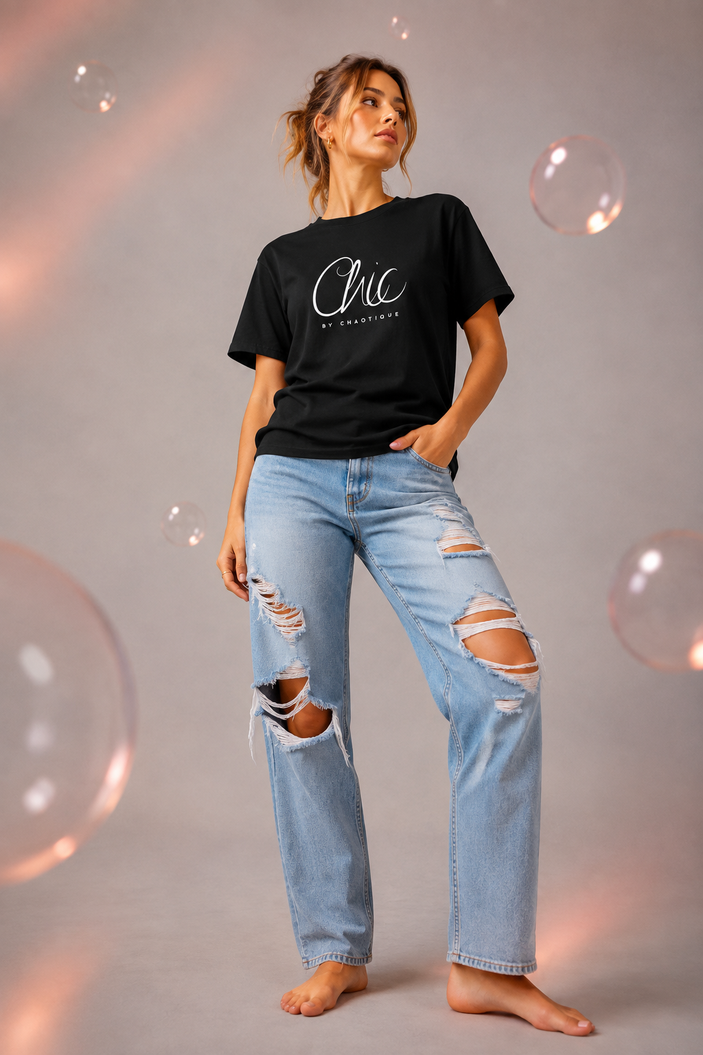 Woman wearing a black Chic by Chaotique graphic T-shirt with light blue ripped jeans in a modern studio setting.