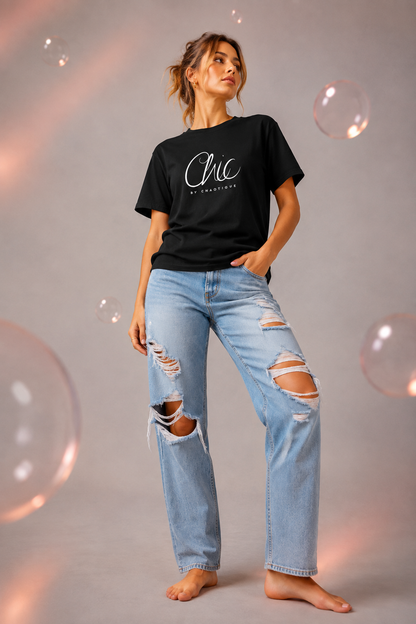 Woman wearing a black Chic by Chaotique graphic T-shirt with light blue ripped jeans in a modern studio setting.