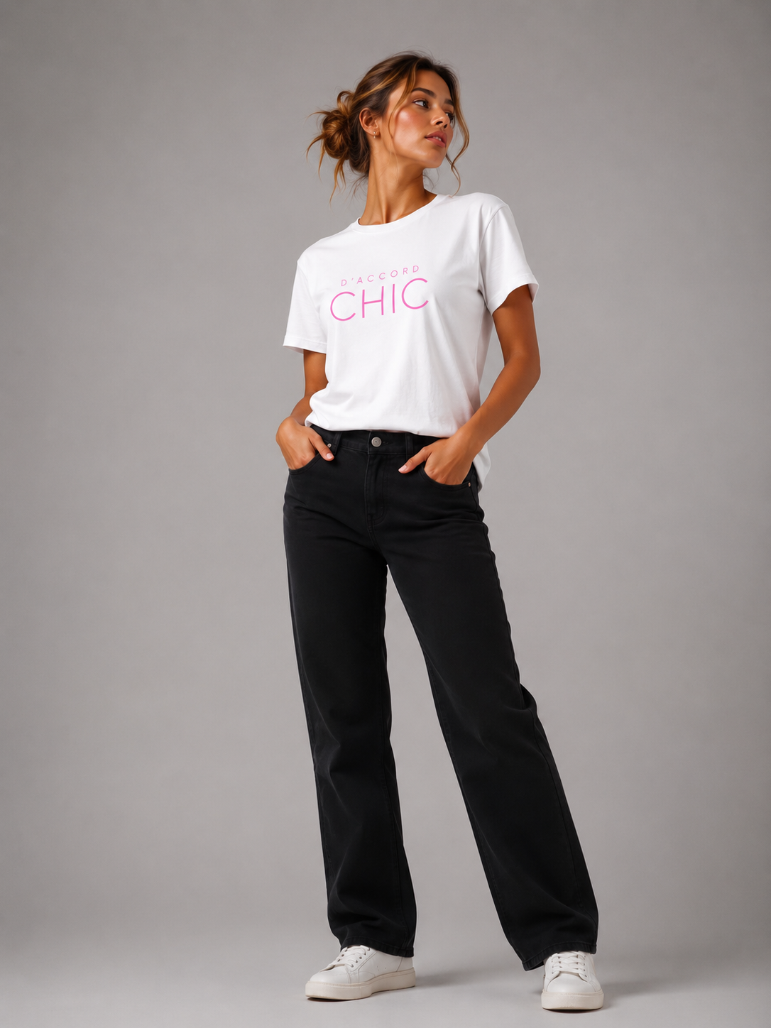 Woman wearing a white D’Accord Chic graphic T-shirt with bold pink typography in a modern studio setting.