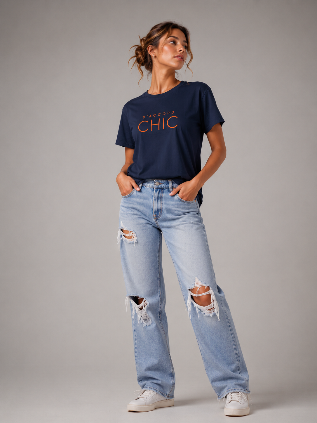Woman wearing a navy blue D’Accord Chic graphic T-shirt with bold orange typography in a modern studio setting.