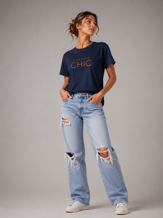 Woman wearing a navy blue D’Accord Chic graphic T-shirt with bold orange typography in a modern studio setting.