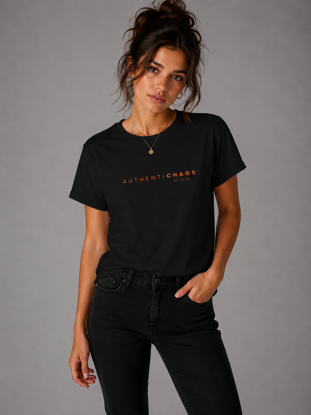 Woman wearing an AuthentiCHAOS by CHTQ graphic T-shirt with minimalist typography in a studio setting.