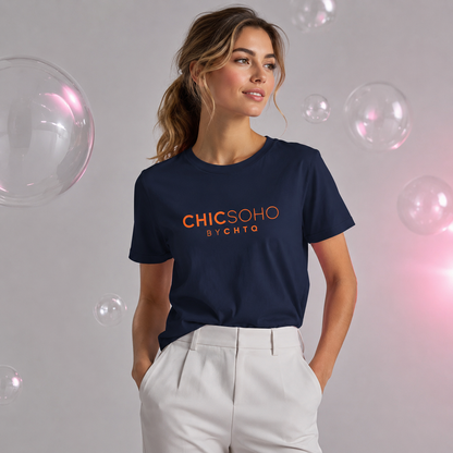 Woman wearing a navy blue CHICSOHO graphic T-shirt with orange logo text and white trousers in a light gray editorial studio with floating bubbles.