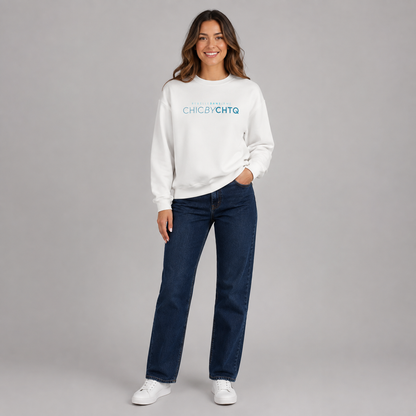 A woman modeling a white crewneck sweatshirt with turquoise text reading “CHIC BY CHTQ” and “REBELLE DANS L’ÂME” above it, paired with light blue jeans and white sneakers against a light gray studio background.