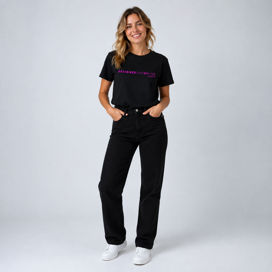 A woman modeling a dark chocolate brown short-sleeve T-shirt with orange text reading “DESIGNED OUT OF LINE” and “BY CHTQ”, paired with black jeans and white sneakers, against a cool light gray studio background.