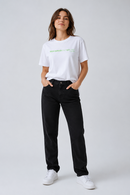 A woman modeling a white crewneck T-shirt with green text that reads “DESIGNED OUT OF LINE” and “BY CHTQ” across the chest, paired with black jeans and white sneakers, against a light gray studio background.