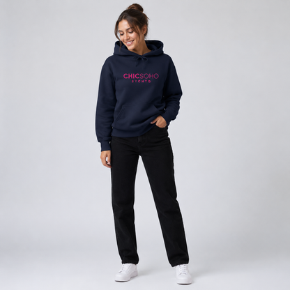 A woman modeling a navy blue pullover hoodie with “CHICSOHO BY CHTQ” printed in pink across the chest, paired with black pants and white sneakers, against a light gray studio background.
