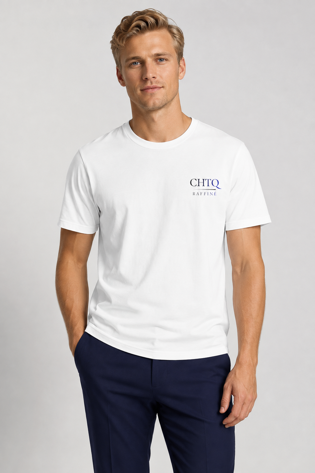 A man wearing a white short-sleeve crewneck t-shirt with a blue 'CHTQ RAFFINE' logo on the left chest, paired with navy blue trousers, against a light gray studio background.