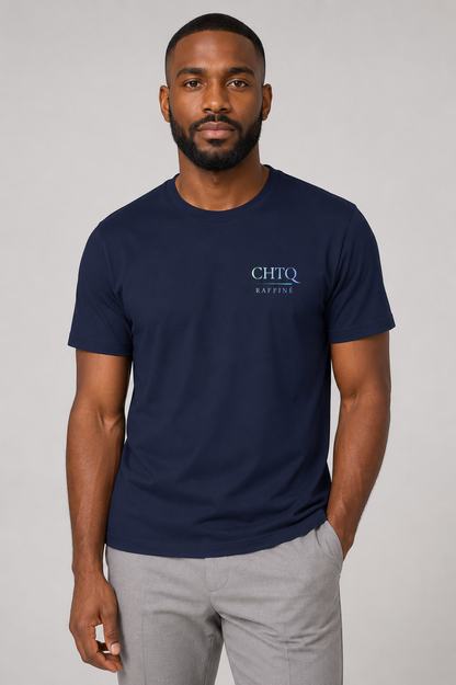 A man wearing a navy blue crewneck t-shirt with a small light blue 'CHTQ RAFFINE' logo on the left chest, paired with light gray trousers, against a neutral gray background.