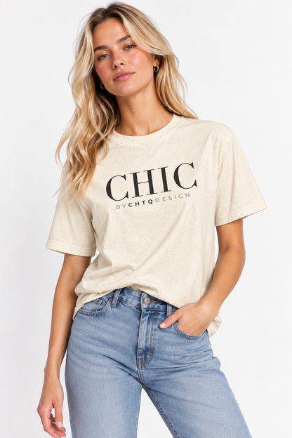 A woman wearing a beige CHIC by CHTQ Design graphic T-shirt with black typography, paired with light blue jeans against a clean white studio background.